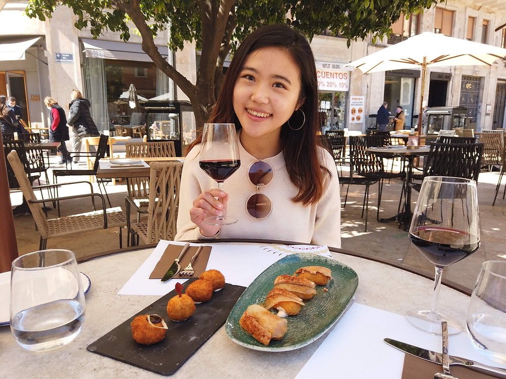 A woman Sat at a Table with a Glass of Red Wine